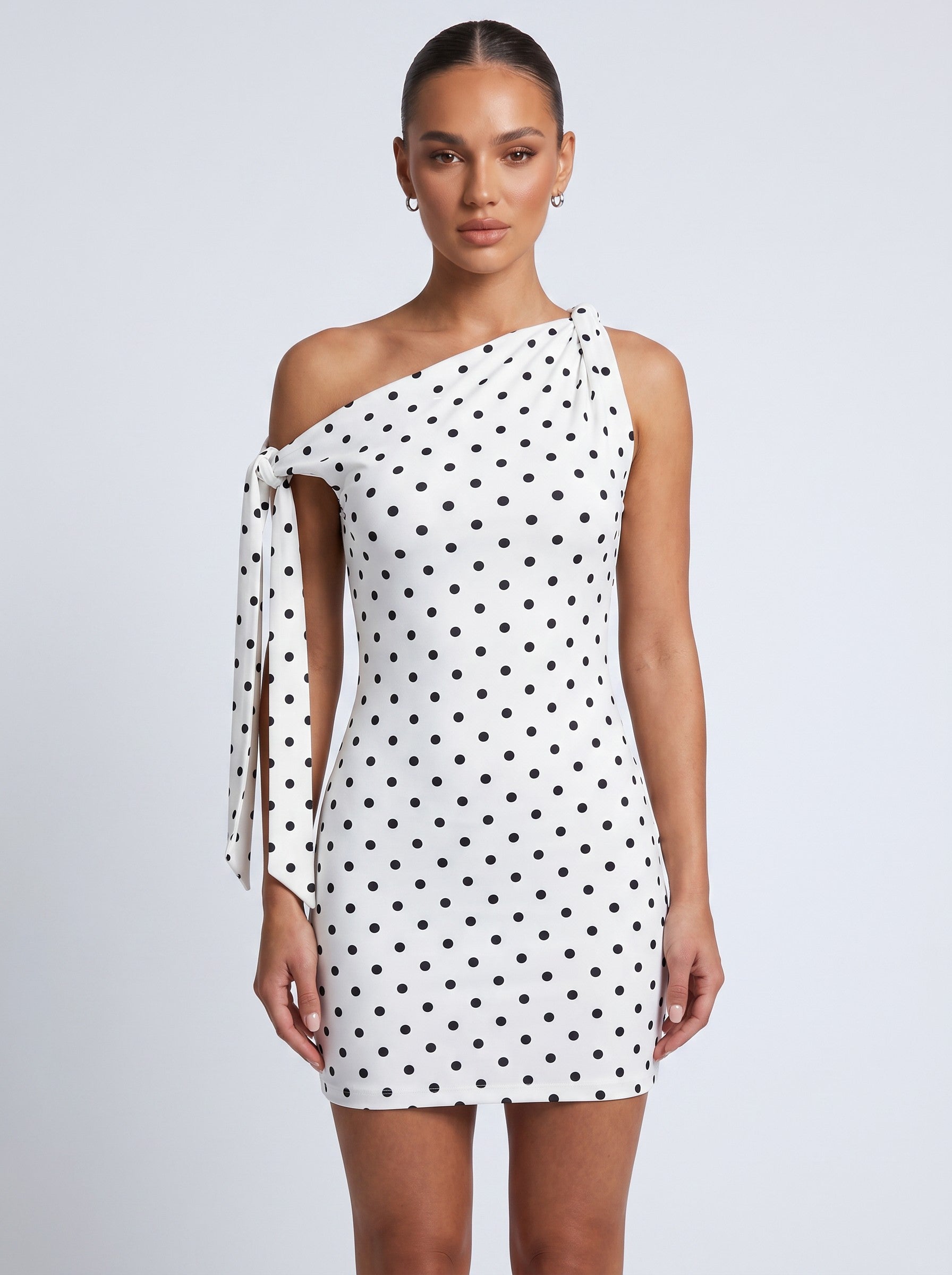 Brisconti Portofino Clara Midikleid in Weiß mit schwarzen Polka-Dots, asymmetrischem Ausschnitt und Schleifendetail.