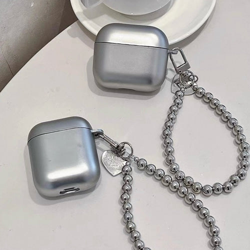 Brisconti Portofino AirPods-Schutzhülle in Metallic-Silber mit Perlenarmband und Herz-Anhänger auf weißem Tisch