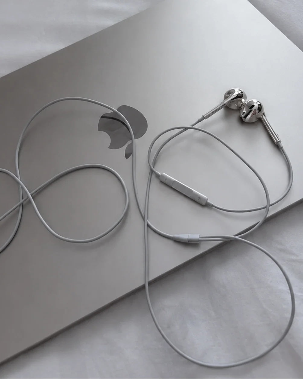Brisconti Portofino verchromte In-Ear-Kopfhörer mit Kabel auf einem silbernen Laptop
